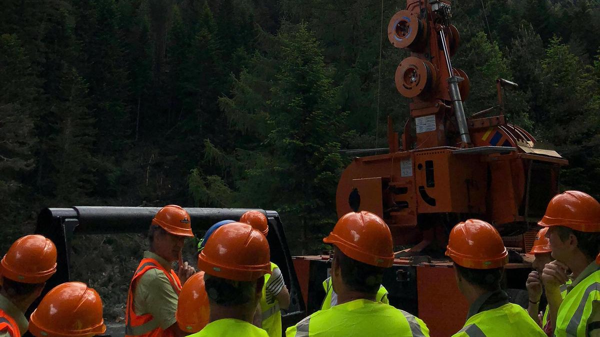 Plusieurs élus en gilet jaune et casques de chantier regardent le câble aérien